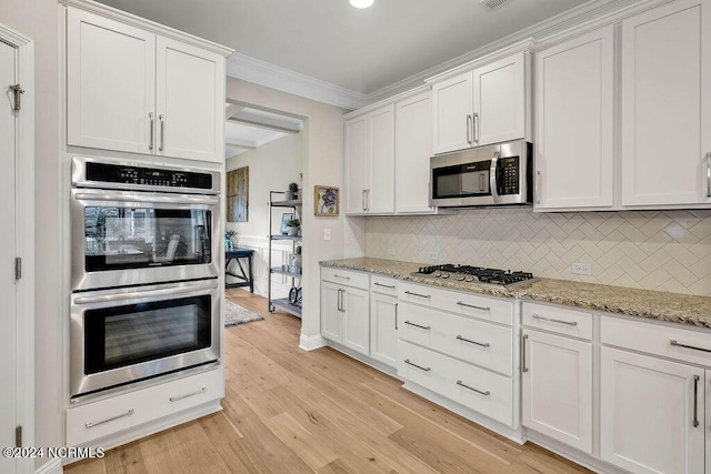 kitchen with white cabinets, light stone countertops, stainless steel appliances, and tasteful backsplash