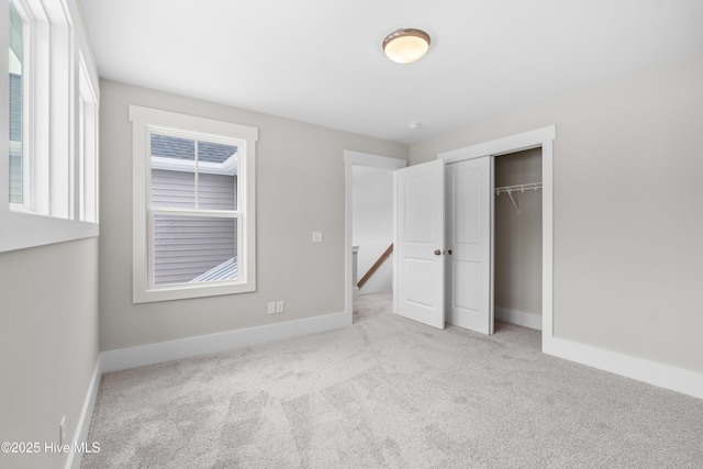 unfurnished bedroom with a closet and light colored carpet