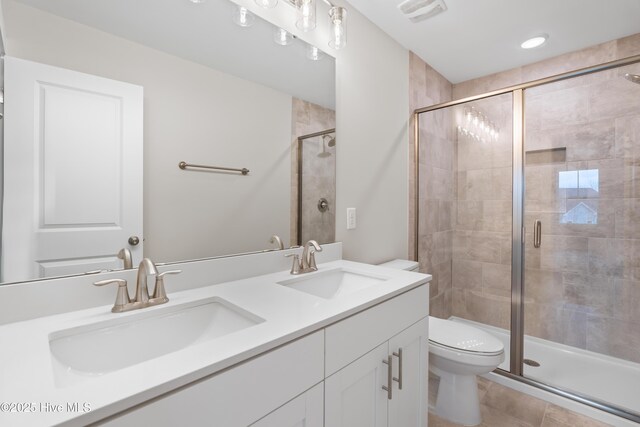 bathroom featuring vanity, toilet, and a shower with door