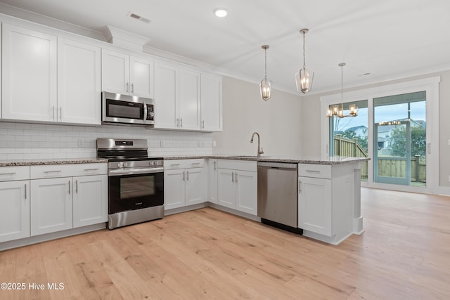 kitchen with white cabinetry, hanging light fixtures, and stainless steel appliances