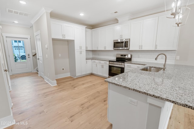 kitchen with backsplash, light stone counters, stainless steel appliances, sink, and white cabinets