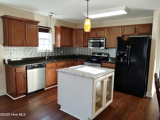 kitchen with dark wood-type flooring, sink, decorative light fixtures, a kitchen island, and stainless steel appliances