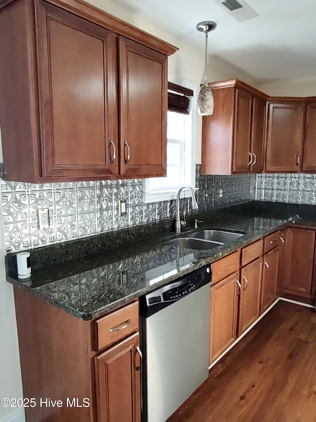 kitchen with dishwasher, dark stone counters, decorative light fixtures, and sink