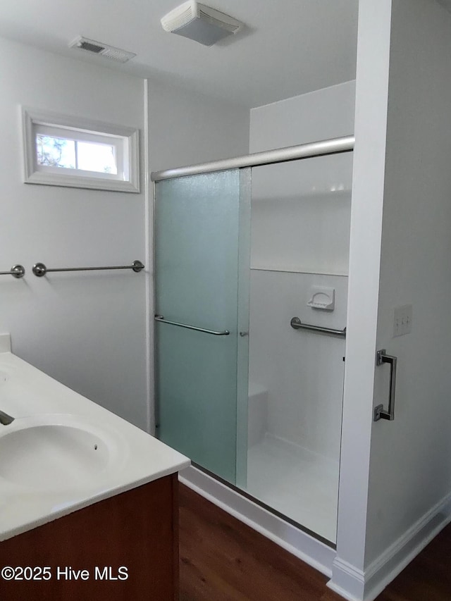 bathroom with hardwood / wood-style flooring, vanity, and walk in shower