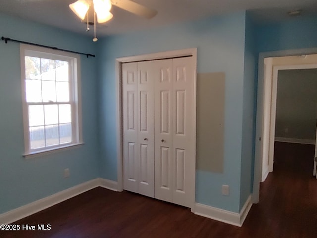 unfurnished bedroom featuring multiple windows, ceiling fan, a closet, and dark hardwood / wood-style flooring