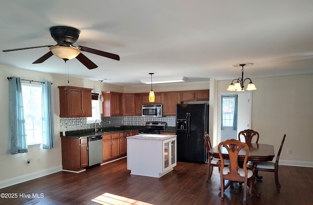 kitchen featuring sink, dark hardwood / wood-style floors, decorative light fixtures, a kitchen island, and appliances with stainless steel finishes