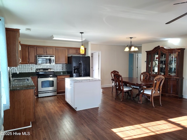 kitchen featuring pendant lighting, a center island, stainless steel appliances, and an inviting chandelier