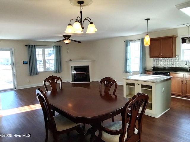 dining area with ceiling fan with notable chandelier, dark wood-type flooring, and sink