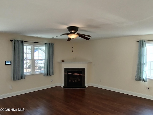 unfurnished living room featuring a wealth of natural light, dark wood-type flooring, and ceiling fan