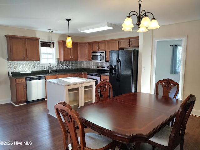 kitchen featuring a center island, dark wood-type flooring, an inviting chandelier, hanging light fixtures, and stainless steel appliances