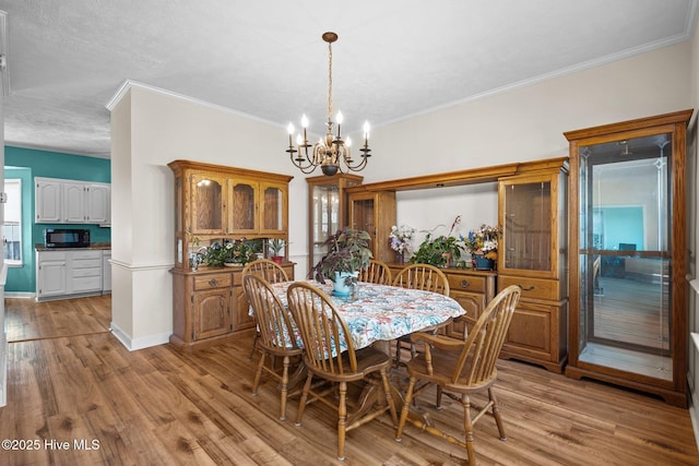 dining area with ornamental molding, a chandelier, and light wood-type flooring