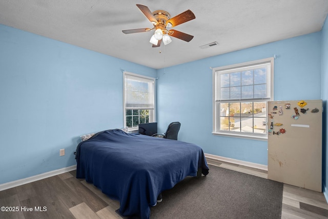 bedroom featuring multiple windows, hardwood / wood-style floors, a textured ceiling, and ceiling fan