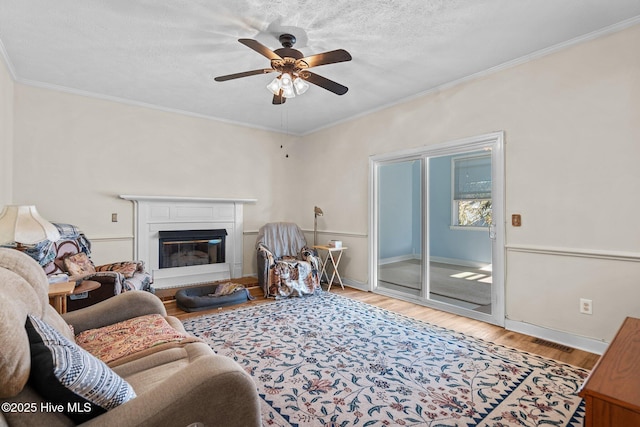 living room featuring crown molding, ceiling fan, wood-type flooring, and a textured ceiling