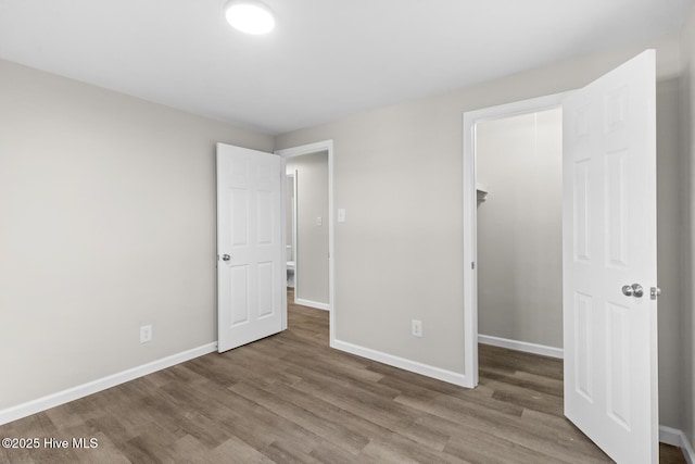 unfurnished bedroom with a closet, a spacious closet, and hardwood / wood-style floors