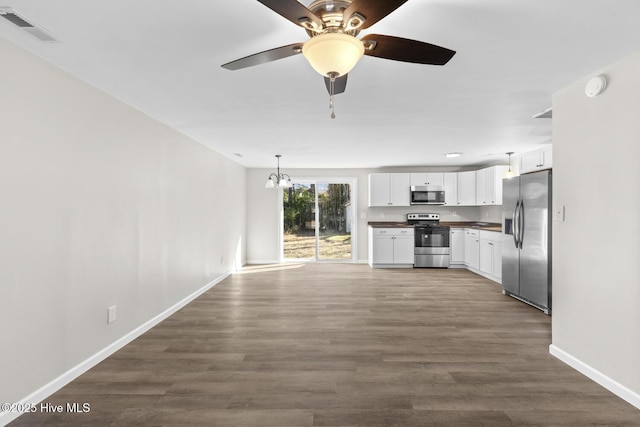 unfurnished living room with ceiling fan with notable chandelier and dark wood-type flooring