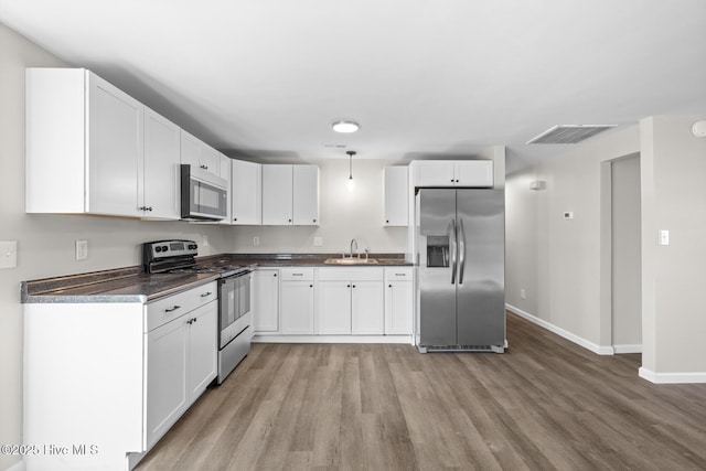 kitchen with white cabinetry, sink, stainless steel appliances, light hardwood / wood-style flooring, and decorative light fixtures