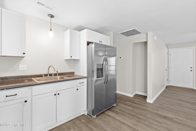 kitchen with light wood-type flooring, sink, pendant lighting, stainless steel fridge with ice dispenser, and white cabinetry