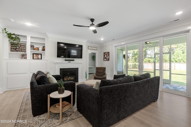 living room with ceiling fan, light wood-type flooring, and crown molding