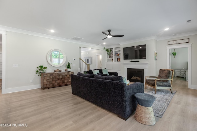 living room featuring light wood-type flooring, built in features, ceiling fan, and ornamental molding