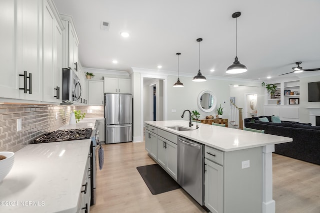 kitchen with sink, an island with sink, hanging light fixtures, and appliances with stainless steel finishes