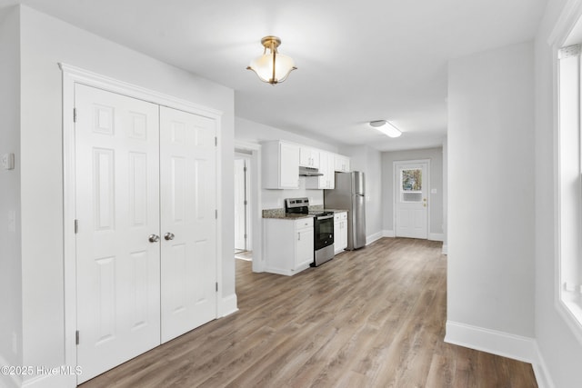 kitchen with white cabinetry, stainless steel appliances, stone countertops, and light hardwood / wood-style floors