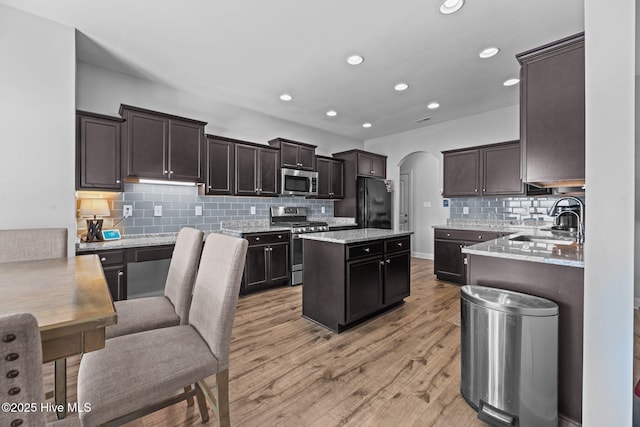 kitchen featuring dark brown cabinetry, sink, light hardwood / wood-style flooring, a kitchen island, and appliances with stainless steel finishes