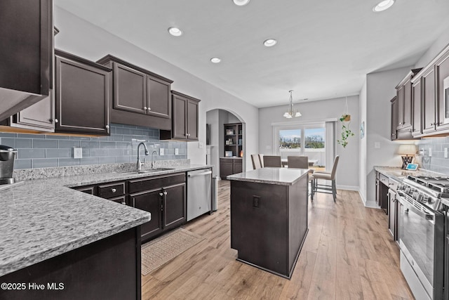 kitchen featuring pendant lighting, backsplash, light stone countertops, a kitchen island, and stainless steel appliances