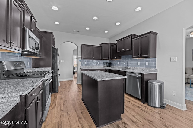 kitchen featuring appliances with stainless steel finishes, a center island, light hardwood / wood-style flooring, and light stone counters