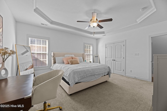 carpeted bedroom with multiple windows, a raised ceiling, ceiling fan, and ornamental molding