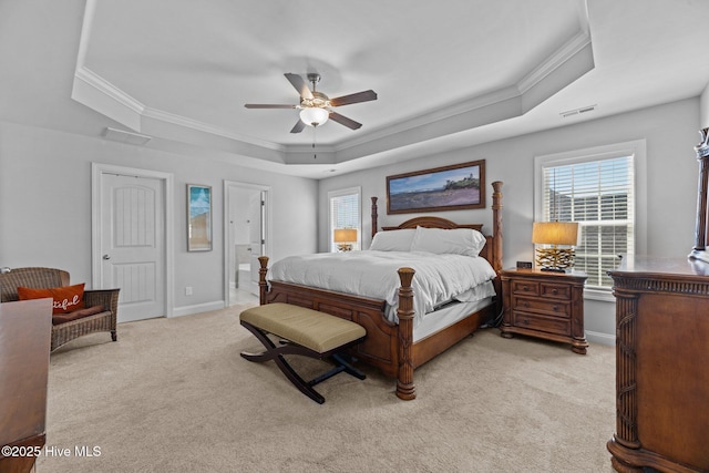 bedroom with light carpet, ensuite bath, a tray ceiling, ceiling fan, and crown molding