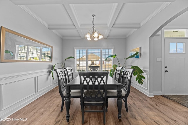 dining space featuring beam ceiling, a healthy amount of sunlight, coffered ceiling, and an inviting chandelier