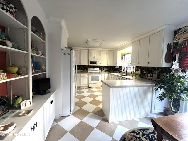 kitchen with white appliances, white cabinets, sink, decorative backsplash, and kitchen peninsula