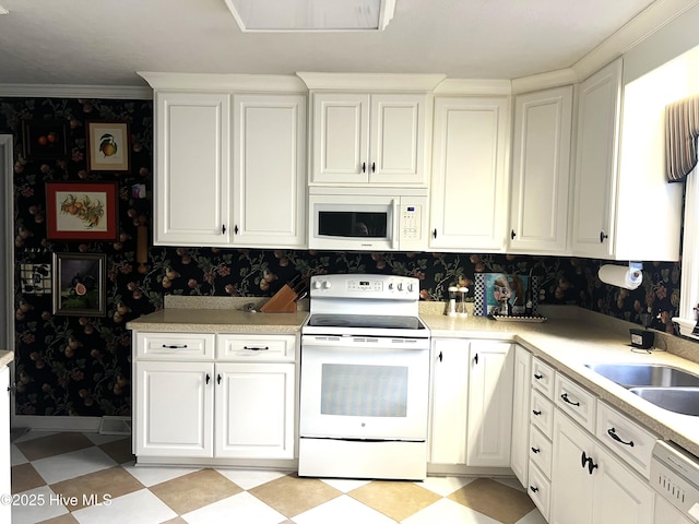 kitchen with white appliances, white cabinetry, crown molding, and sink