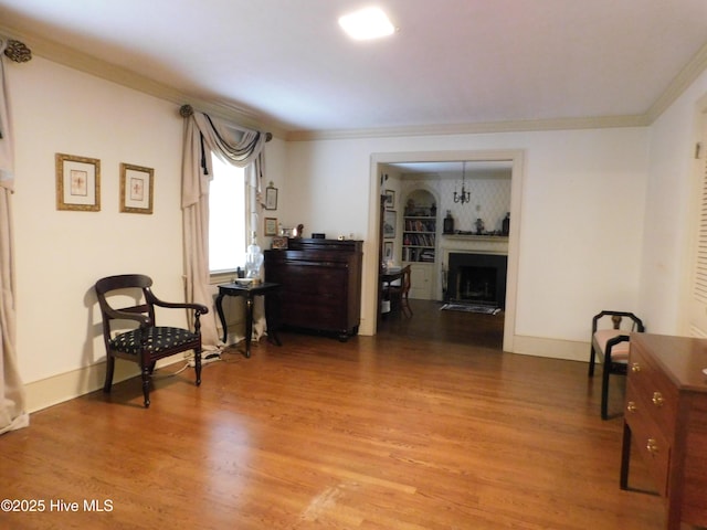 sitting room with hardwood / wood-style flooring and crown molding