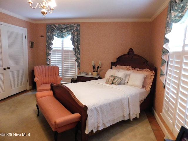 carpeted bedroom with a closet, a chandelier, and ornamental molding