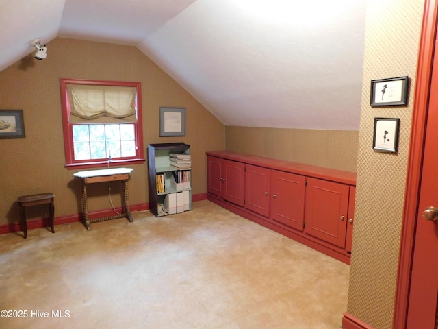 bonus room with light colored carpet and vaulted ceiling