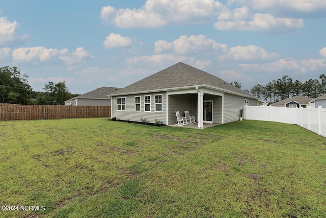 rear view of house featuring a yard and a patio