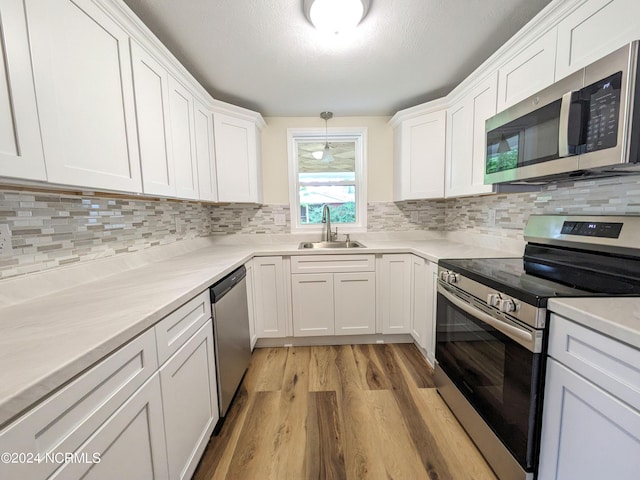 kitchen with sink, white cabinets, hanging light fixtures, and appliances with stainless steel finishes