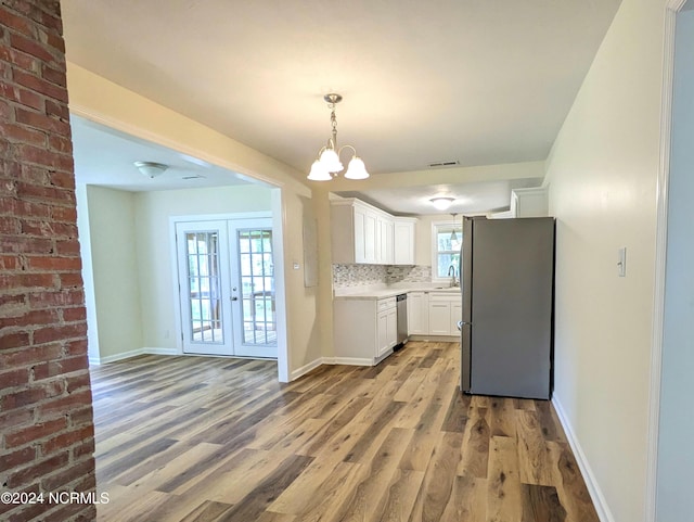 kitchen with french doors, hardwood / wood-style flooring, tasteful backsplash, white cabinetry, and stainless steel appliances