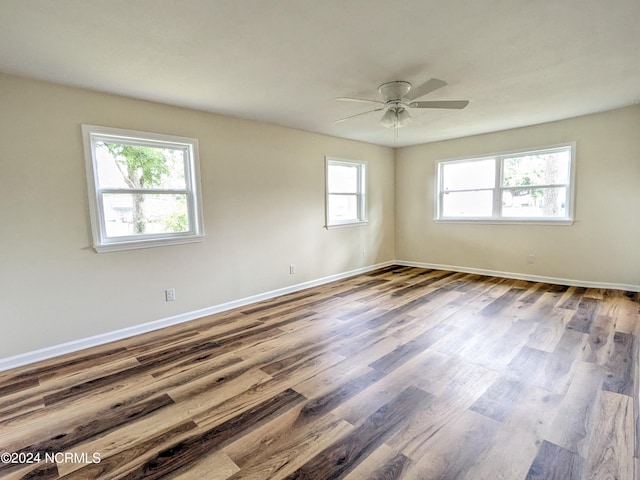 empty room featuring ceiling fan, a healthy amount of sunlight, and wood-type flooring