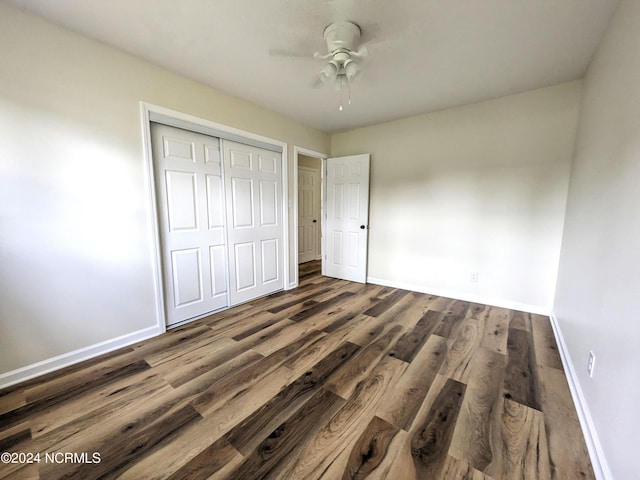 unfurnished bedroom with ceiling fan, a closet, and dark wood-type flooring