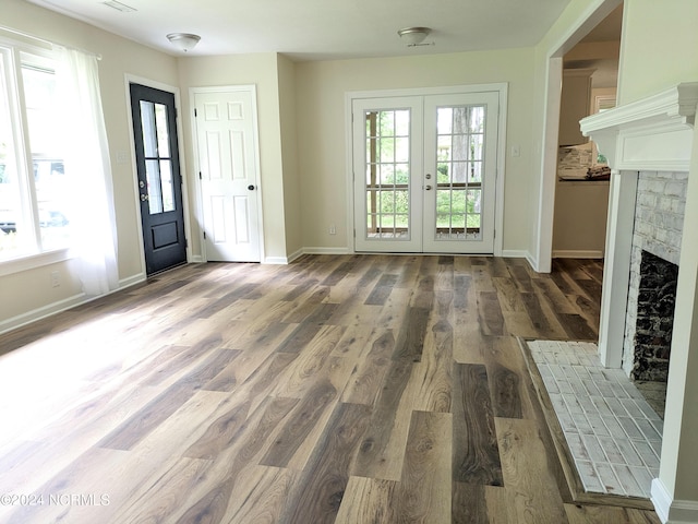 doorway to outside with plenty of natural light, dark hardwood / wood-style floors, and a brick fireplace