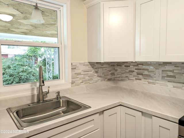 kitchen with white cabinetry, hanging light fixtures, and sink