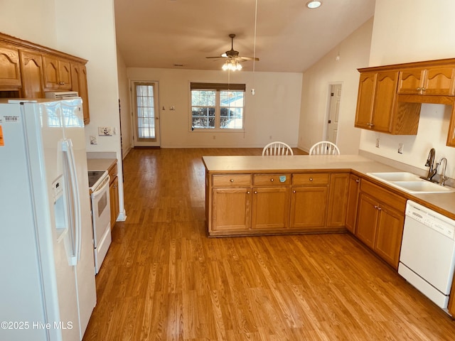 kitchen featuring sink, white appliances, light hardwood / wood-style floors, and kitchen peninsula