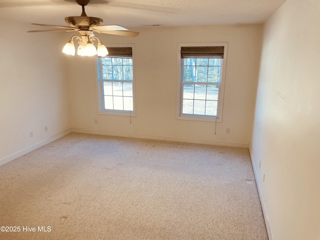 carpeted spare room featuring ceiling fan and a wealth of natural light