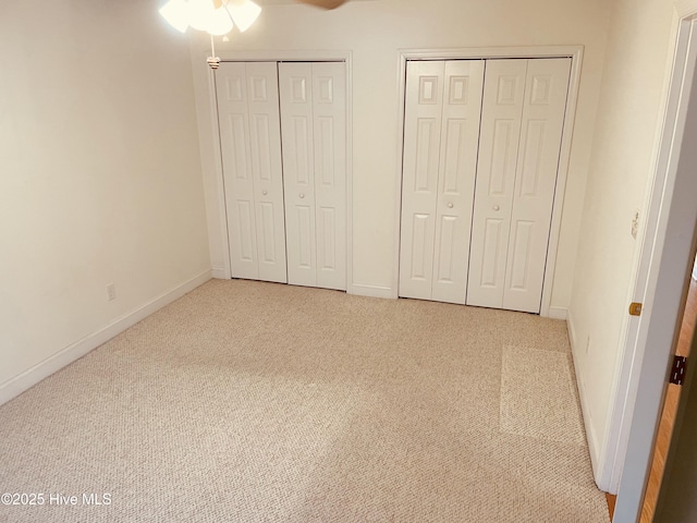 unfurnished bedroom featuring two closets and light carpet