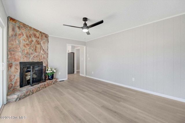 unfurnished living room featuring ornamental molding, ceiling fan, a fireplace, and light hardwood / wood-style flooring