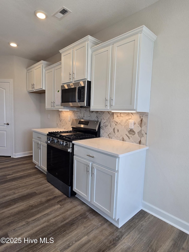 kitchen featuring white cabinetry, backsplash, appliances with stainless steel finishes, and dark hardwood / wood-style flooring