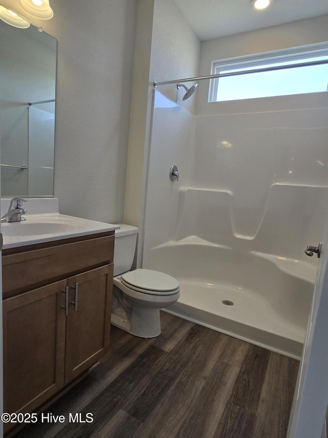 bathroom featuring hardwood / wood-style floors, toilet, vanity, and walk in shower