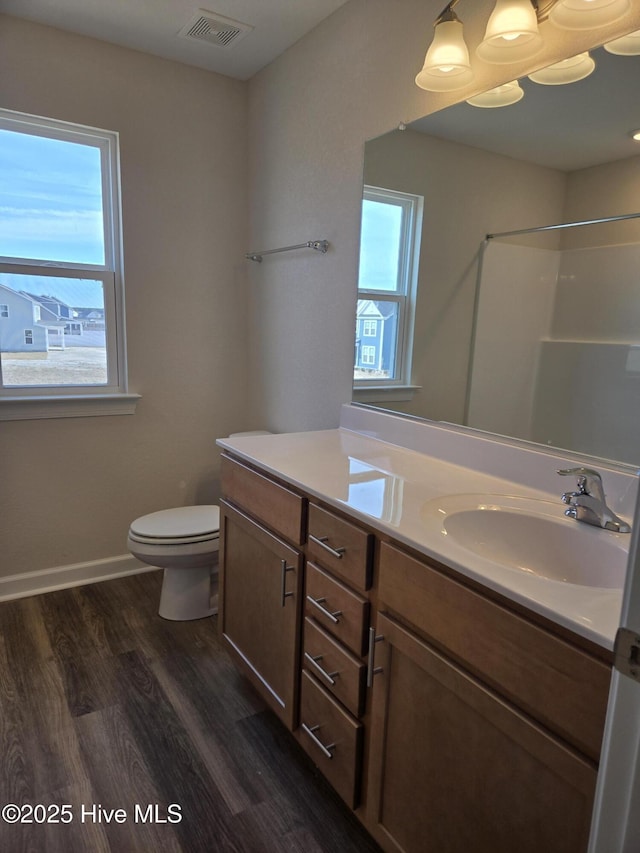 bathroom with a shower, a wealth of natural light, wood-type flooring, and vanity